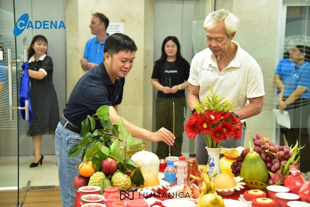Two team members lighting incense in front of the opening offerings, colleagues standing behind